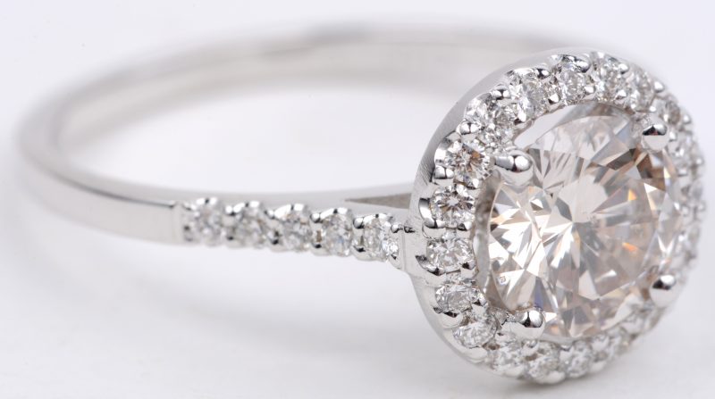 Een 18 karaats wit gouden ring bezet met diamanten met een gezamenlijk gewicht van ± 0,30 ct. en een centrale solitair van ± 1,04 ct.