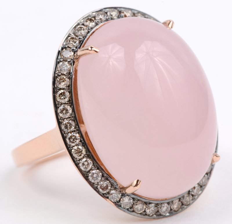 Een 18 karaats wit en rooskleurige gouden ring bezet met diamanten met een gezamenlijk gewicht van ± 0,52 ct. en een roze kwarts cabochon van ± 16,67 ct.