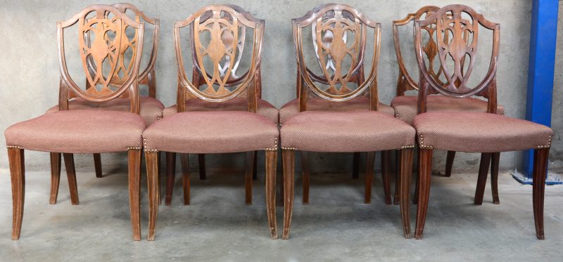 Een reeks van acht mahoniehouten stoelen met stoffen bekleding.