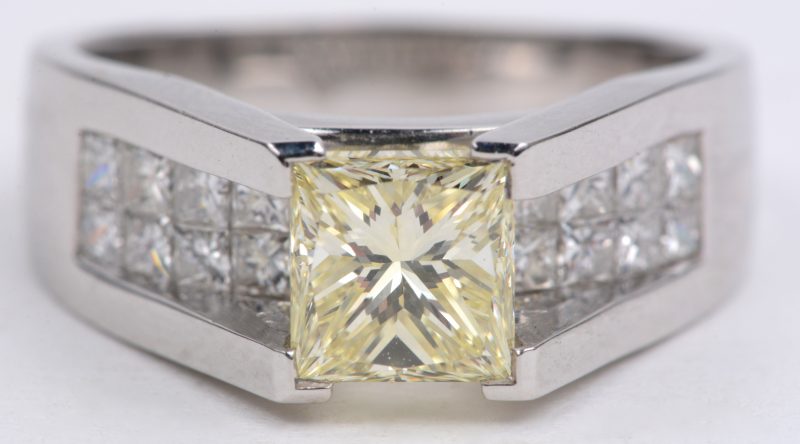 Een 18 karaats wit gouden ring bezet met 22 diamanten princess cut met een gezamenlijk gewicht van ± 0,90 ct. en een centrale fancy color diamant princess cut van ± 1,40 ct. V.S. En met certificaat HRD Antwerpen.