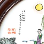 Een plaquette van Chinees porselein in houten lijst met een meerkleurig decor van een personage in een tuin.