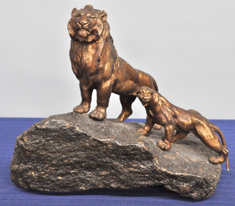 “Leeuwenpaar op een rotsblok van natuursteen”. Groep van brons met een goudgeel patina. Gesigneerd op de rotsblok.