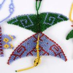 Elf verschillende kleurrijke handgemaakte halssnoeren met hangers in de vorm van insekten en dieren. Artesania Mujer Matsigenka.