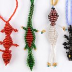 Elf verschillende kleurrijke handgemaakte halssnoeren met hangers in de vorm van insekten en dieren. Artesania Mujer Matsigenka.