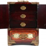 Een Chinees juwelenkabinetje van hout en koper en versierd met plaquettes van jade.