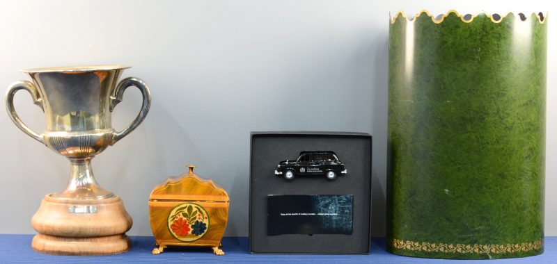 Een lot varia, bestaande uit een verzilverde trofee, een gepolychromeerd metalen doosje, een schaalmodel van een Londense taxi als bedrijfsgeschenk en een groengepatineerde koperen paaraplubak.