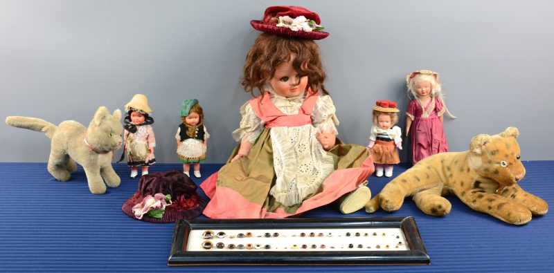 Een lot speelgoed, bestaande uit twee pluchen diertjesn twee popenhoeden, een pop van Unica, vier kleine popjes en een kader met oude kunstglazen ogen.