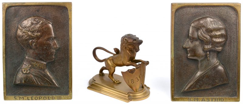 Een paar plaquettes met de beeltenissen van Koning Leopold III en Koningin Astrid. Gesigneerd ‘A. Darimont’. We voegen er een bronzen leeuwtje met schild ter gelegenheid van het vijftigjarig bestaan van België aan toe.