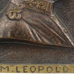 Een paar plaquettes met de beeltenissen van Koning Leopold III en Koningin Astrid. Gesigneerd ‘A. Darimont’. We voegen er een bronzen leeuwtje met schild ter gelegenheid van het vijftigjarig bestaan van België aan toe.