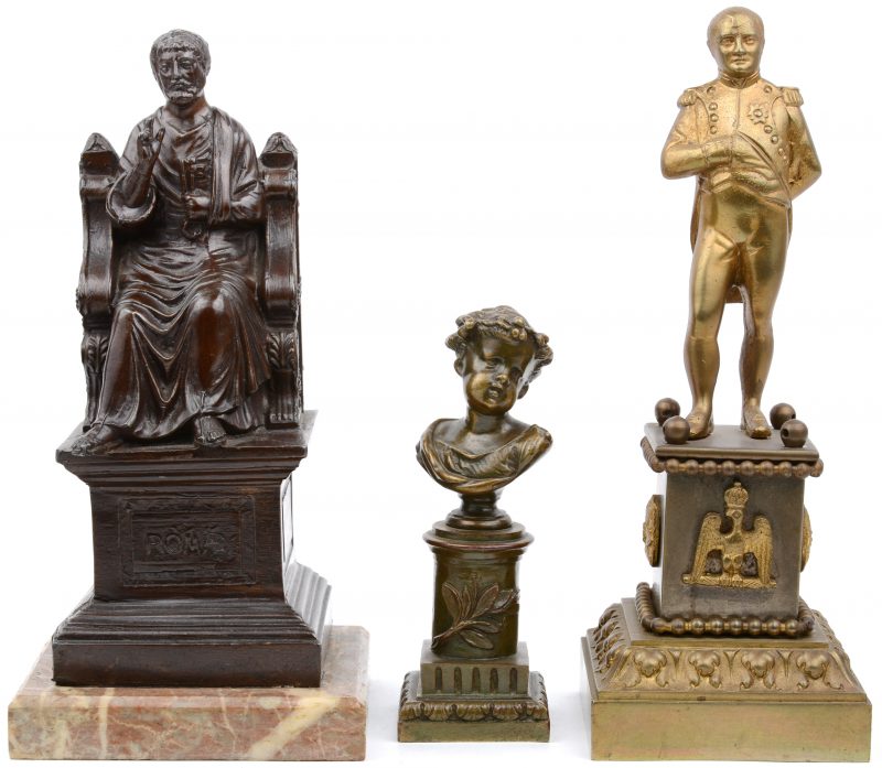 Een lot van drie beeldjes, bestaande uit een bronzen jongensbuste, een bronzen voorstelling van Napoleon en een Romeins keizer van zamak op marmeren sokkel.