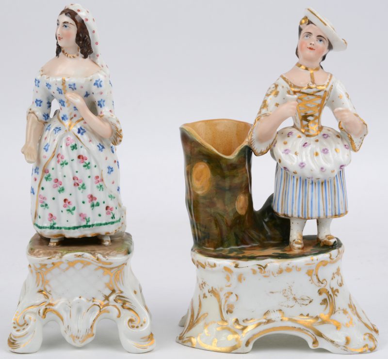 “Dame met hoed bij boomstronk” & “Jonge vrouw met jurk”. Twee beeldjes van meerkleurig en verguld porselein op voetstuk. Niet gemerkt. Eind XIXe eeuw.