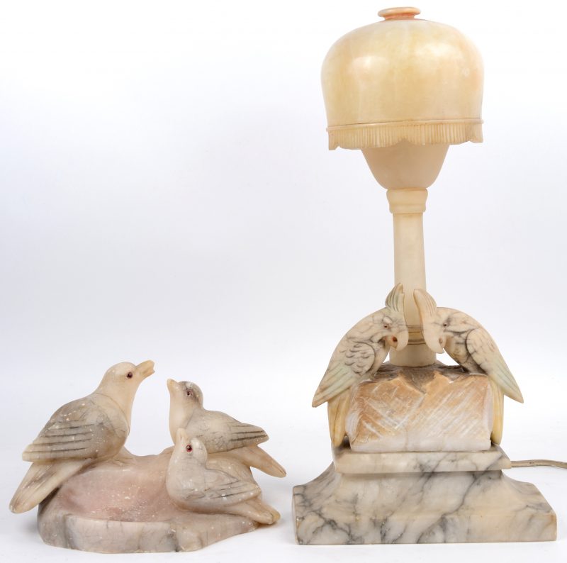 Een asbak en een lampje van gesculpteerd albast, beide versierd met vogels met glazen oogjes.