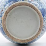 Een vaas van blauw, wit en rood porselein met een decor van mythologische wezens.