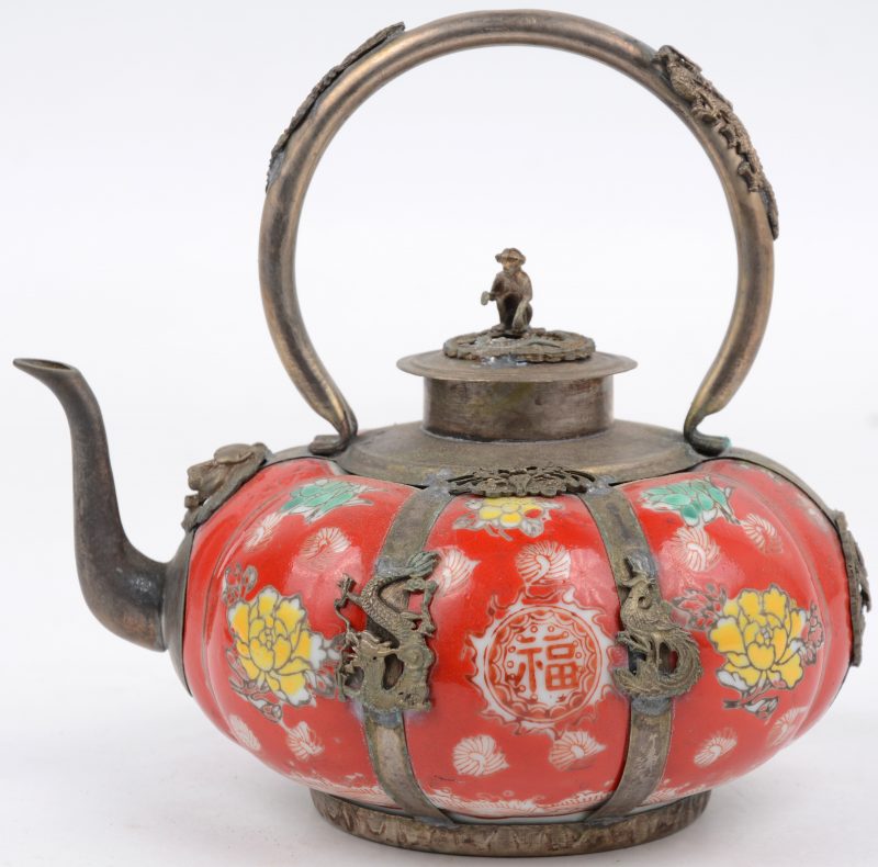 Een pompoenvormig theepotje van Chinees porselein en verzilverd koper met een meerkleurig decor van bloemen op een rode fond en het dekesltje getooid met een aapje.