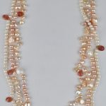 Een drie rijen halssnoer van witte en roze parels met zilveren slot.