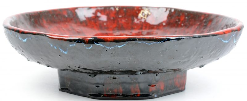 Een achtkantige schaal van rood en zwart geglazuurd Belgisch aardewerk.
