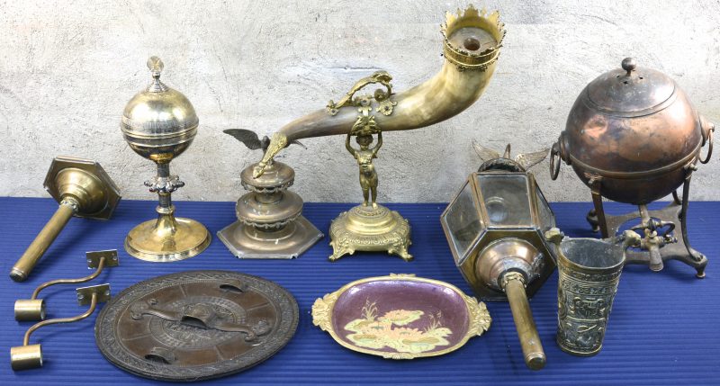 Een lot koper en brons, bestaande uit twee lantaarns (waarvan één zwaar beschadigd), een ciborie, een koehoorn, gedragen door een kindje, een geëmailleerd bord, een vaatje met kraantje, enz.
