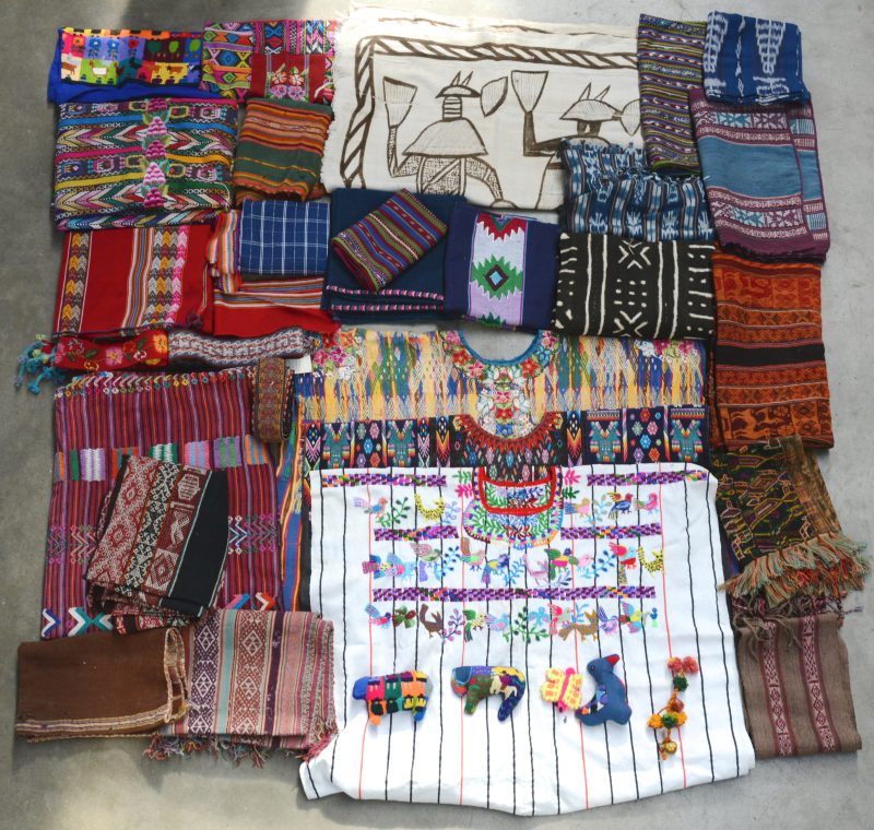 Een grenenhouten koffer met textiel uit Guatemala, Peru, Mali (Senufo) met poncho’s, kleden, sjaals enz.