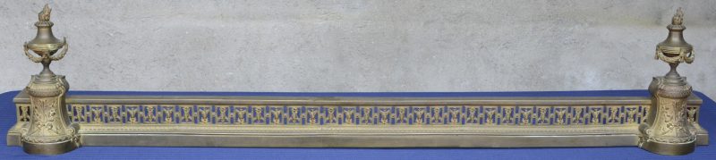 Een haardversiering van brons in empiestijl, versierd met twee siervazen op de hoeken.