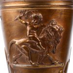 Een paar bronzen siervazen in empirestijl, versierd met een afbeelding van Cupido op een leeuw in reliëf op de buik.
