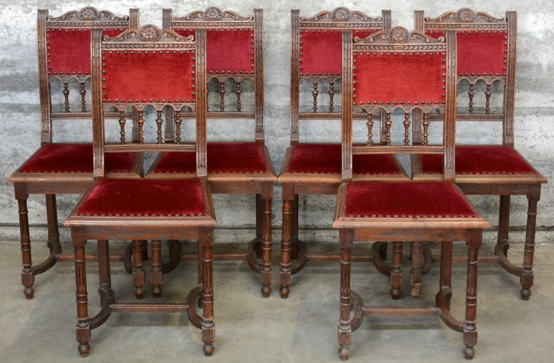 Een reeks van zes stoelen van gesculpteerd eikenhout, bekleed met rood fluweel.