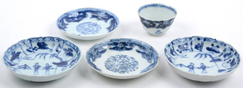 Een kopje met onderbordje en drie andere bordjes van blauw en wit Chinees porselein, waarbij er twee een paar vormen. Tijdperk Qianlong.