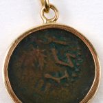 Een bronzen Romeinse munt als hanger gemonteerd in 18 karaats geel goud.