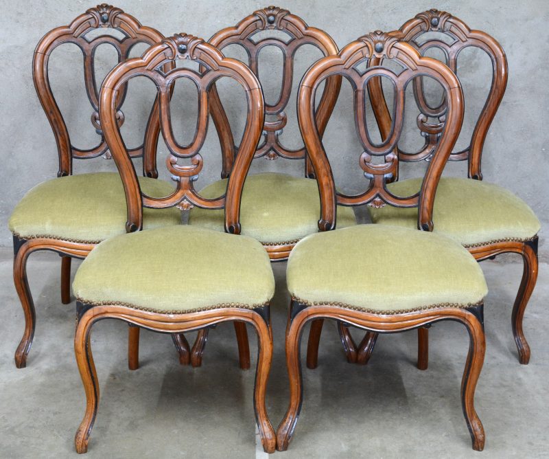 Een serie van vijf stoelen van notenhout, versierd met ebbenhouten details. Voluutpoten vooraan, mooi versierde rug met kuif. Tweede helft XIXde eeuw.
