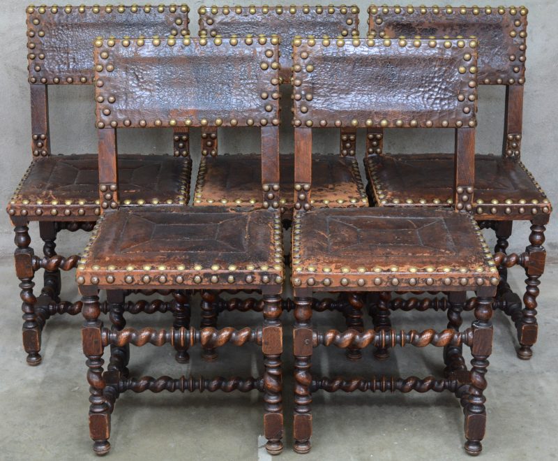 Een serie van 5 eikenhouten renaissancestoelen bekleed met leder en voorzien van grote koperen siernagels. XIXde eeuw.