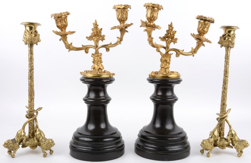 Twee paar kandelaars van verguld brons. Het eerste in met twee lichtpunten in Lodewijk XV-stijl en op houten voetstukken, het tweede paar versierd met ramskoppen en op drie voetjes in de vorm van leeuwen.