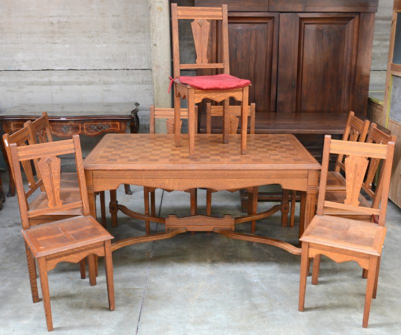 Een eikenhouten tafel met negen bijpassende stoelen. Tijdperk art deco.