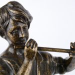 Bronzen beeldje van een fluitspelende jongen.