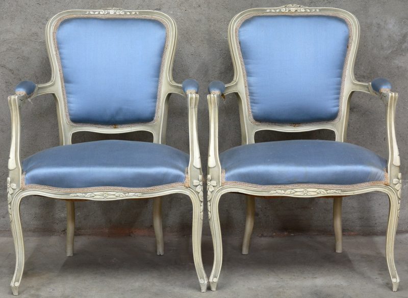 Een paar fauteuils en cabriolet in Lodewijk XV-stijl van witgepatineerd hout met blauwe bekleding.
