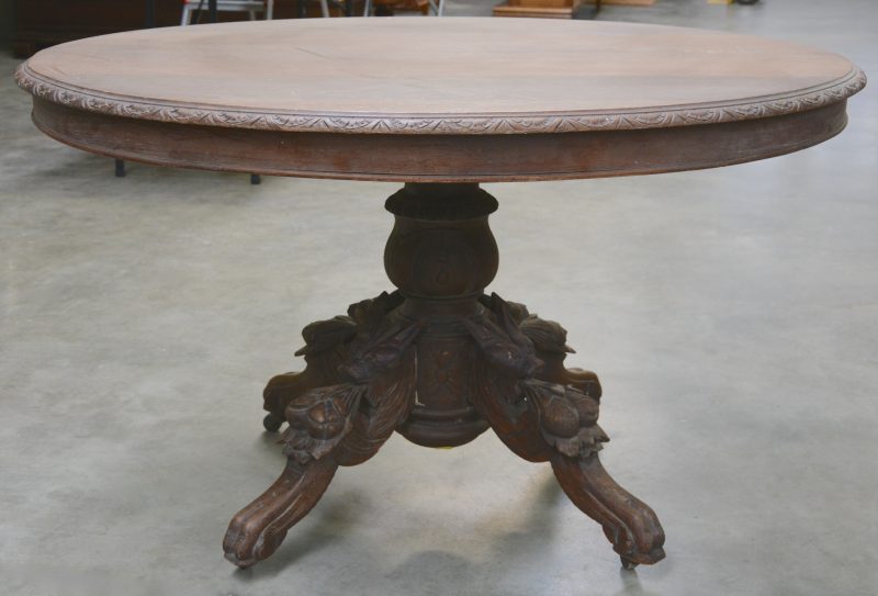 Een ovale tafel van gebeeldhouwd eikenhout, de poot versierd met dierenkoppen en vruchten.