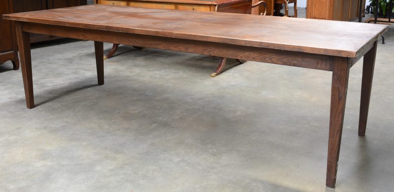 Een grote tafel van tropisch hout met vier tapse poten.