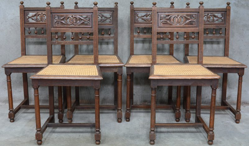 Een reeks van zes stoelen van gebeeldhouwd hout met gecanneerde zit.