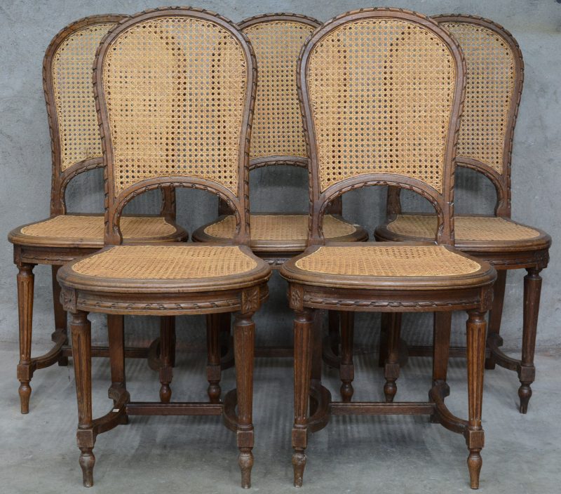 Een reeks van vijf stoelen van gesculpteerd hout in Lodewijk XVI-stijl met gecanneerde rug en zit.