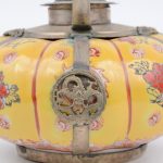Een pompoenvormig theepotje van meerkleurig Chinees porselein met verzilverde monturen.