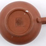 Een theepotje van Chinees terracotta. Onderaan gemerkt. Schilfer aan de tuit en aan de binnenkant van het deksel.