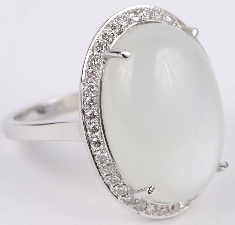 Een 18 karaats wit gouden ring bezet met diamanten met een gezamenlijk gewicht van ± 0,40 ct. en een maansteen van ± 12 ct.