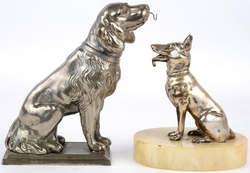 Twee verschillende hondjes van zilvergepatineerd zamak, waarbij één op onyxen voetstuk. Als horlogehangers.