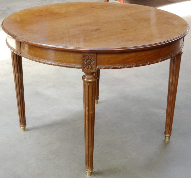Een verlengbare ronde tafel van mahoniehout met gecanneleerde poten.