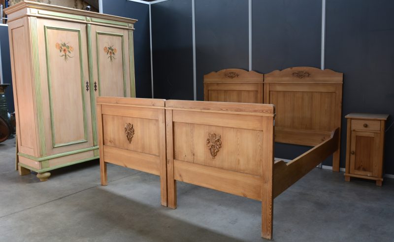 Een grenenhouten slaapkamer, bestaande uit twee eenpersoonsbedden, een garderobe en twee nachtkastjes.