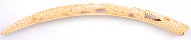 Een gesculpteerde ivoren slagtand in de vorm van een jongen in de bekken van twee krokodillen.