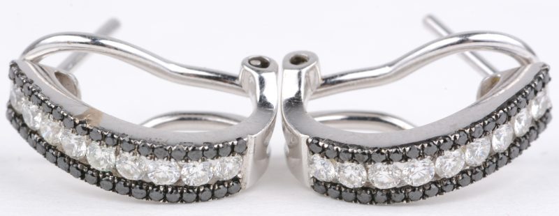 Een paar 18 karaats wit gouden oorbellen bezet met twee kleuren diamant  met een gezamenlijk gewicht van ± 1,50 ct.