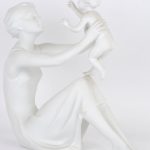“Moeder met kind” & “De fluitspeelster”. Twee beeldjes van monochroom wit biscuit. Beide gemerkt.