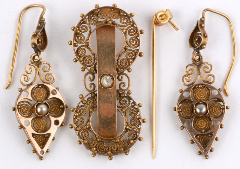 Een paar 18 karaats geel gouden oorbellen met bijpassende te herstellen broche in filigraanwerk en bezet met pareltjes.