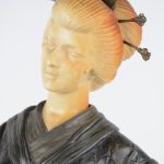 Een lampe met een bleoemvormig kapje, gedragen door een geisha van zamak en ivoirine op een voetstuk van meersoortig marmer.