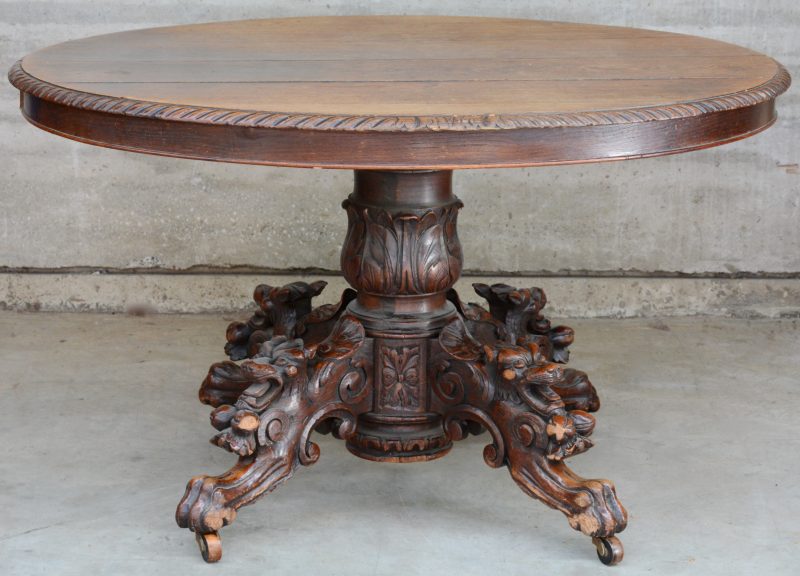 Een ronde tafel van gesculpteerd eikenhout, de vier poten versierd met vossenkoppen. XIXe eeuw.