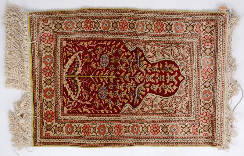 Een klein Perzisch wandkleedje van zijde met twee vogels van goudbrokaat in de mirab.
